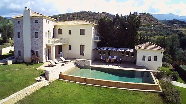 A large house with a swimming pool, multiple balconies, and a garden.