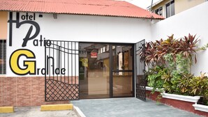 A hotel entrance with a glass door, a metal gate, and potted plants. - Hotel Patio Grande (Flores)