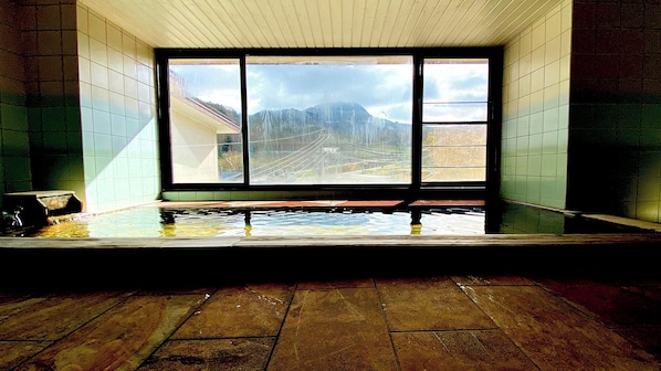 A room with a large window, a wooden floor, and a small pool.