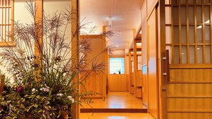 A hallway with wooden doors, a potted plant with flowers, and a window with a view. - Hotel & Onsen 2307 Shigakogen (Yamanouchi)