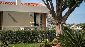 A modern building with a stone facade, a balcony with a railing, and a large tree in the foreground. - Villa 15  Elegant Private Pool Family (Rethymno)
