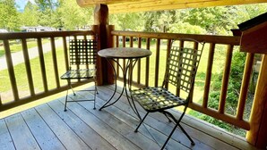 A wooden deck with a table and two chairs, surrounded by a wooden railing. - Idaho Lodge and RV Park (Bonners Ferry)