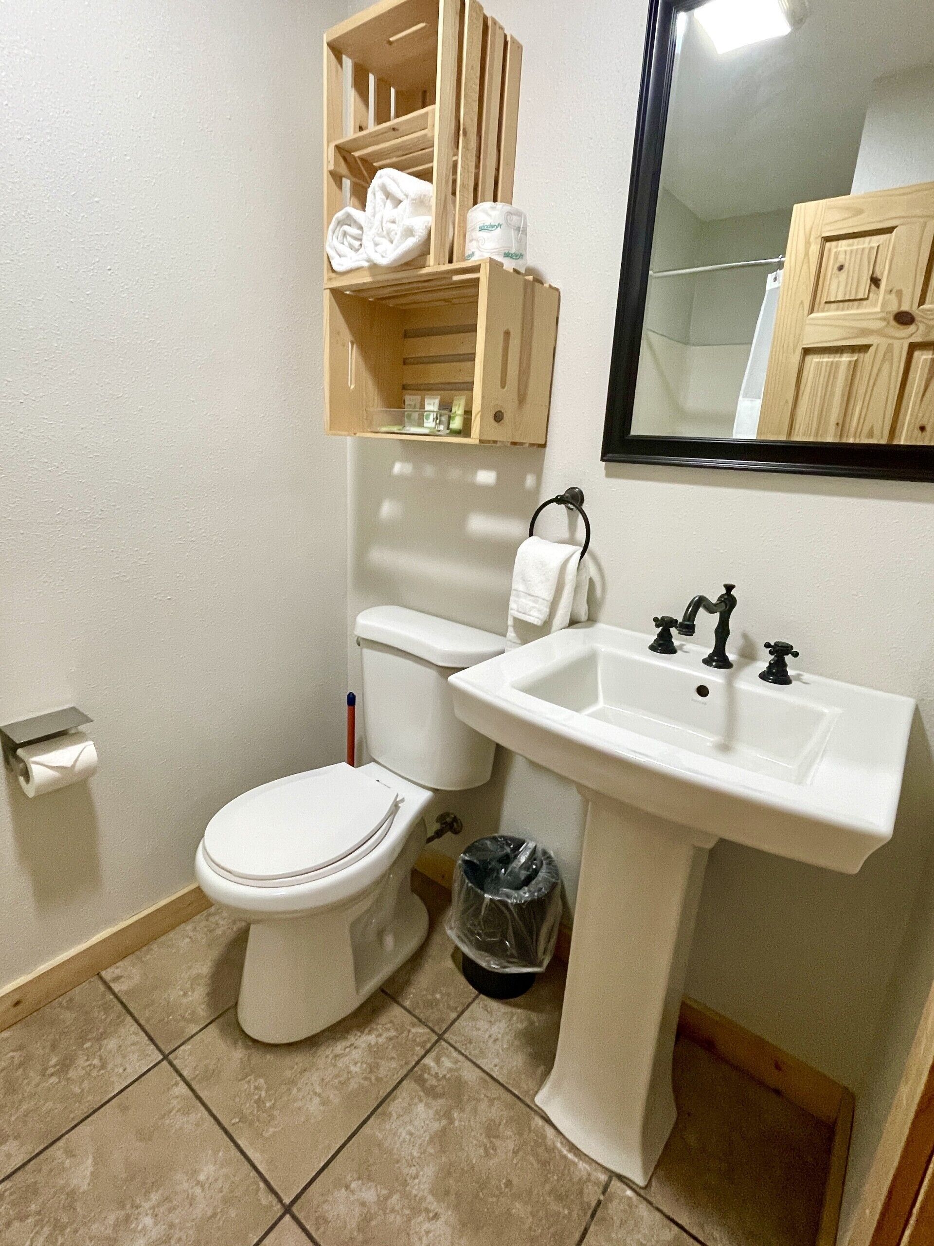 Un baño con inodoro, lavamanos y un mueble de madera sobre el inodoro.
