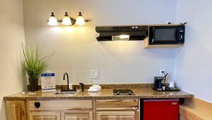 A compact kitchen with wooden cabinets, a red dishwasher, a microwave, and a sink. - Idaho Lodge and RV Park (Bonners Ferry)
