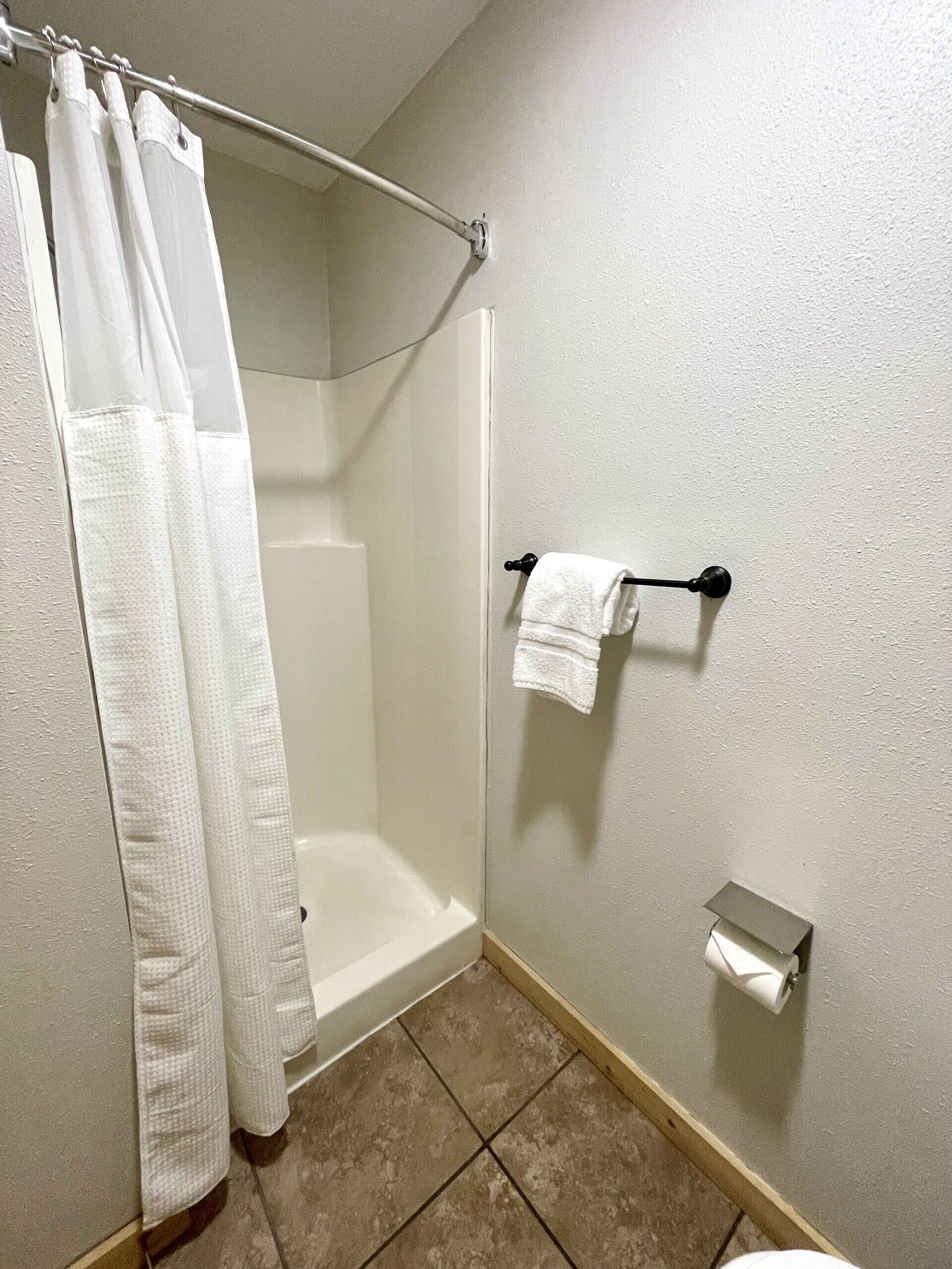 Ein Badezimmer mit Dusche, Handtuchhalter und Toilettenpapierhalter.