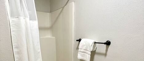 Ein Badezimmer mit Dusche, Handtuchhalter und Toilettenpapierhalter.
