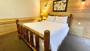 A wooden-framed bed in a room with a wooden wall and a world map. - Idaho Lodge and RV Park (Bonners Ferry)