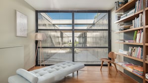 A modern room with a large window, a sofa, a chair, and a bookshelf. - Villa 7 Masterwork Contemporary (Chania)