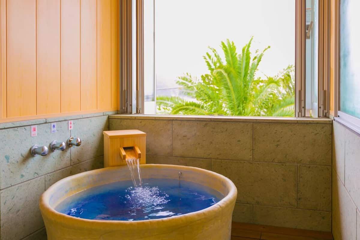 Uma banheira de hidromassagem com água corrente, um armário de madeira e uma janela com vista para o verde.