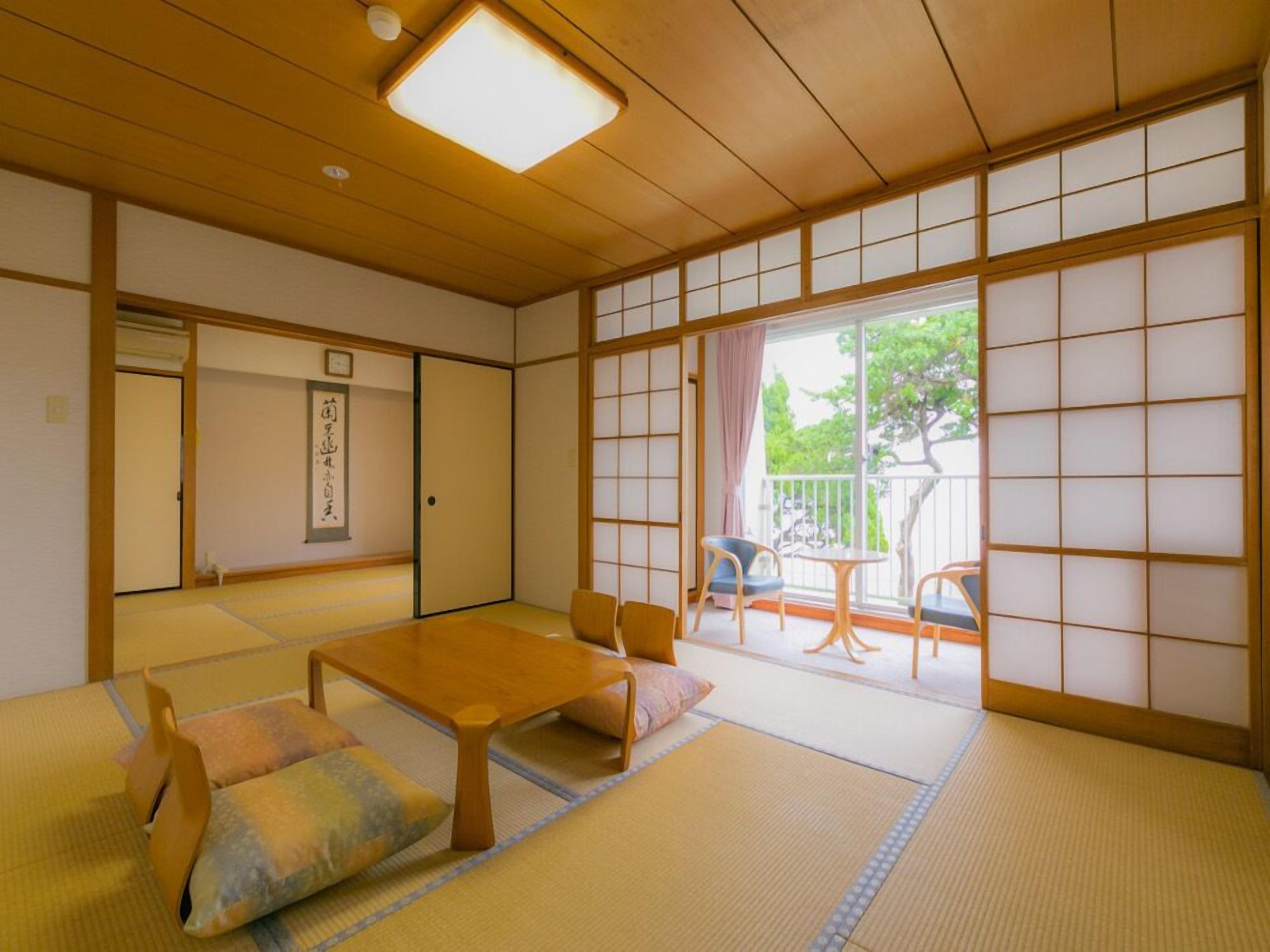 A traditional Japanese room with tatami flooring, a low wooden table, and sliding doors leading to a balcony.