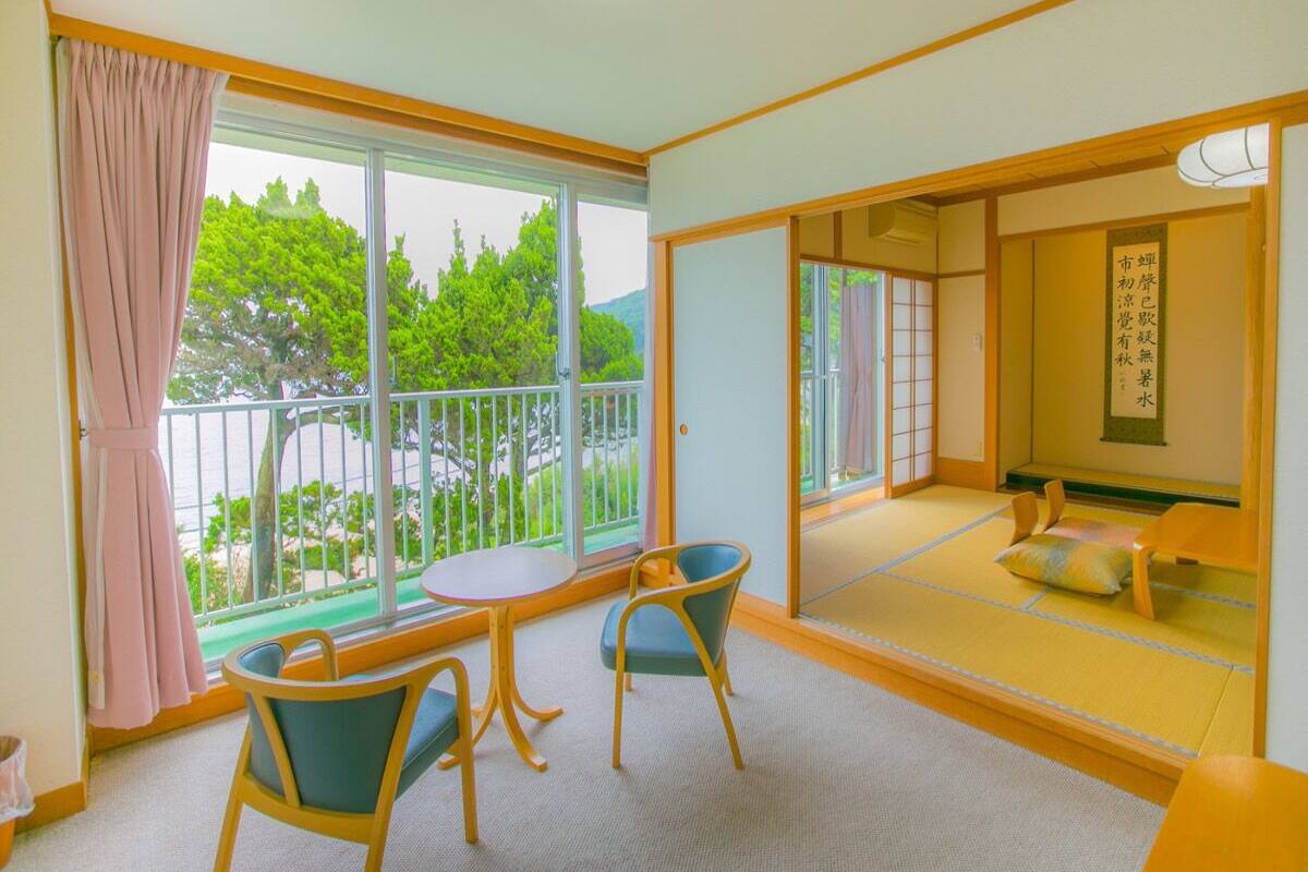Um quarto com piso de tatame, uma porta deslizante para uma varanda e um tradicional biombô japonês.