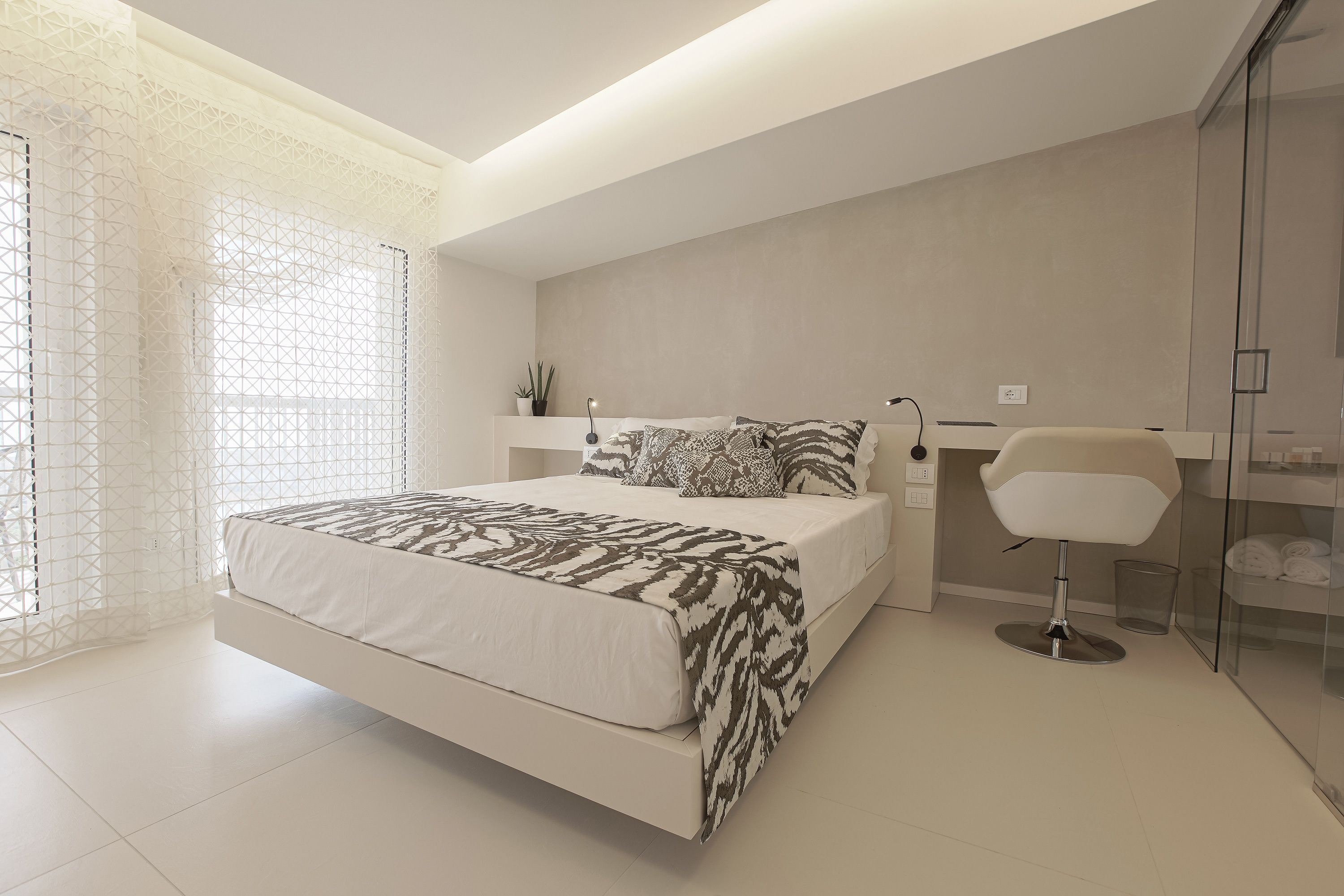 Un dormitorio moderno con una cama grande, una mesita de noche, una silla y un box de ducha de vidrio.