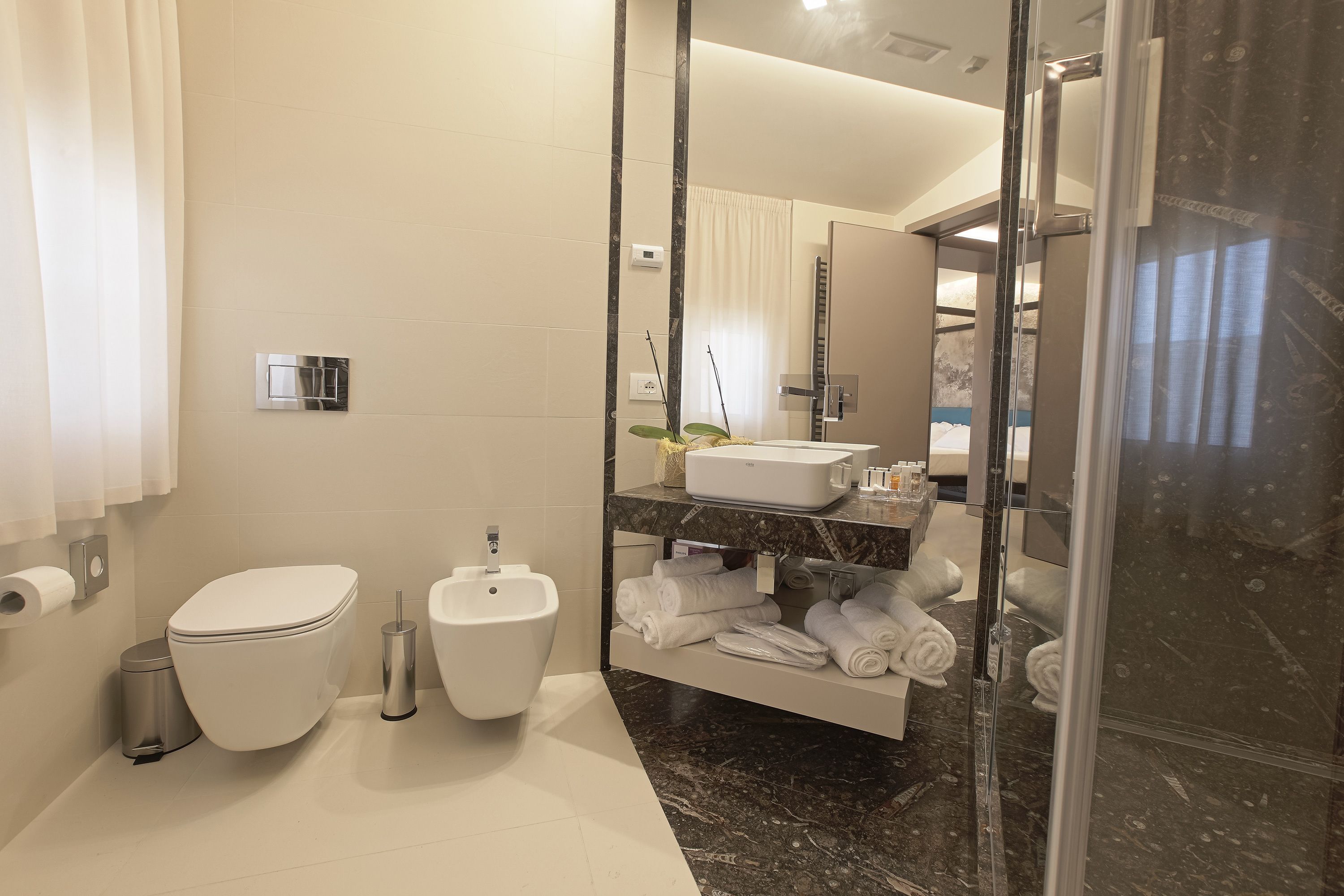 A modern bathroom with a toilet, bidet, and a glass-enclosed shower area.