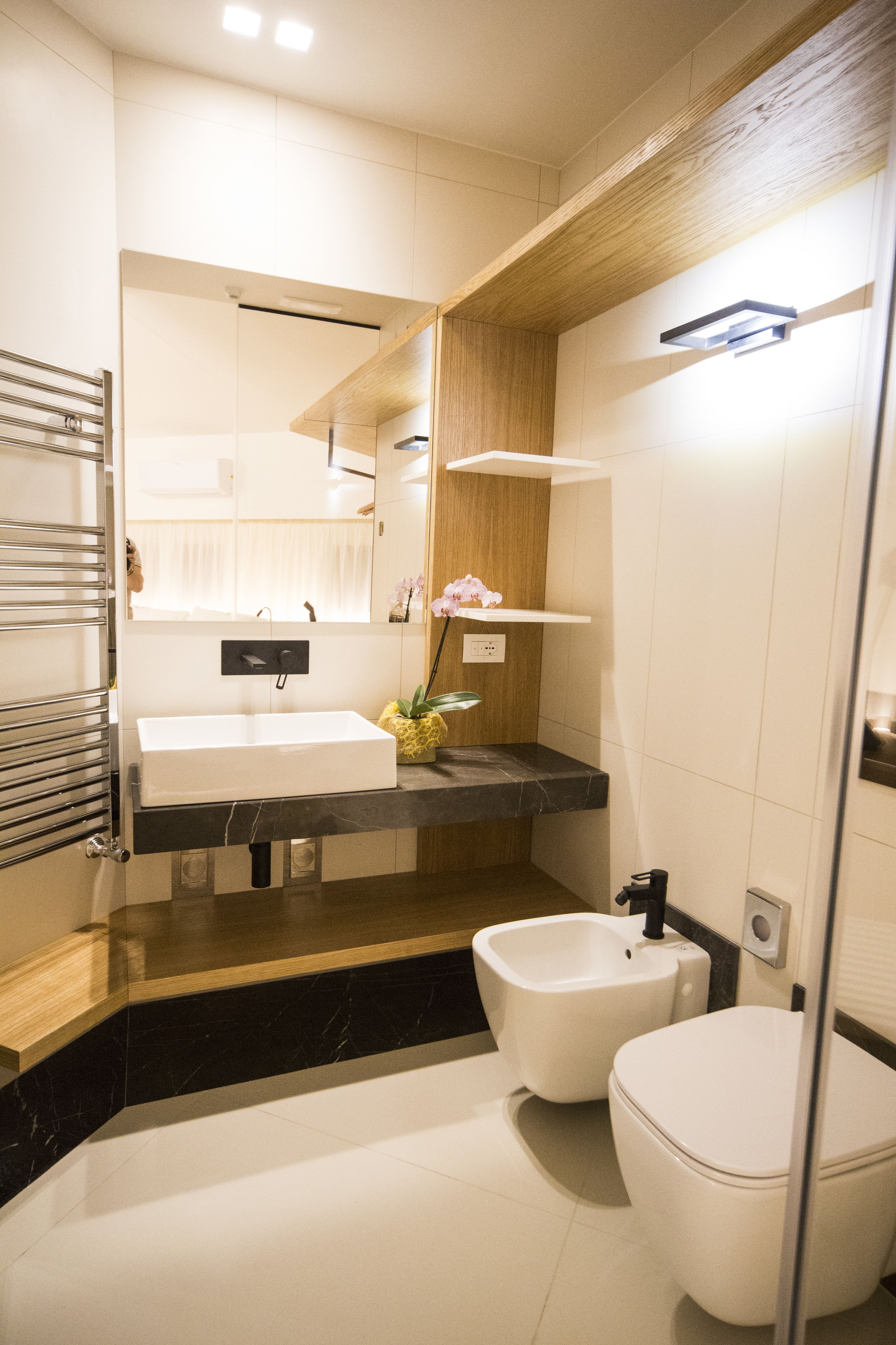 A modern bathroom with a white sink, bidet, and toilet.