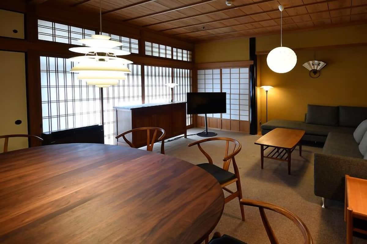 Ein traditioneller japanischer Raum mit Tatami-Böden, einem niedrigen Tisch, einer Sitzecke und einem Fernseher.