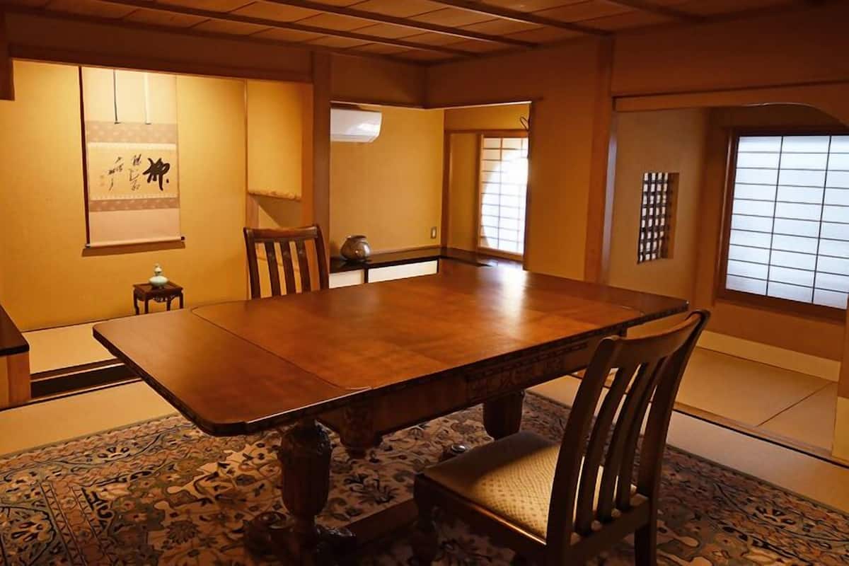 Ein traditioneller japanischer Raum mit Tatami-Bodenbelag, einem Holztisch und einem Shoji-Bildschirm.