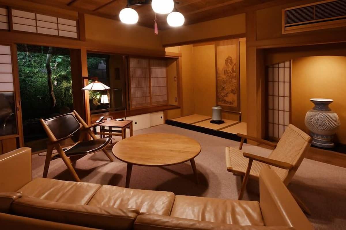 Ein traditioneller japanischer Raum mit Tatami-Boden, einem niedrigen Tisch und einer Couch.