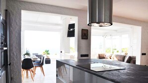 Una cocina moderna con una isla grande, un comedor con mesa y sillas, y vistas al exterior.