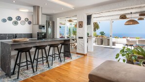 Una cocina moderna con una isla grande, taburetes de bar y vistas al océano.
