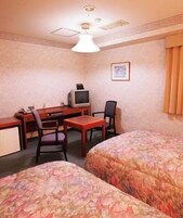 Habitación de hotel con dos camas, un escritorio con televisor y una silla.
