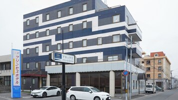 A modern building with a sign for a business hotel and a parking sign.