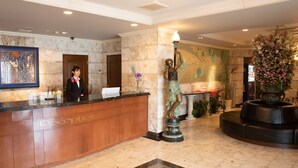 A hotel reception area with a marble reception desk, a receptionist, a statue, and a large floral arrangement. - Hotel Castle inn Tsu (Tsu)