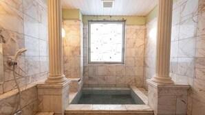 A bathroom with marble walls, a bathtub, and a window. - Hotel Castle inn Tsu (Tsu)