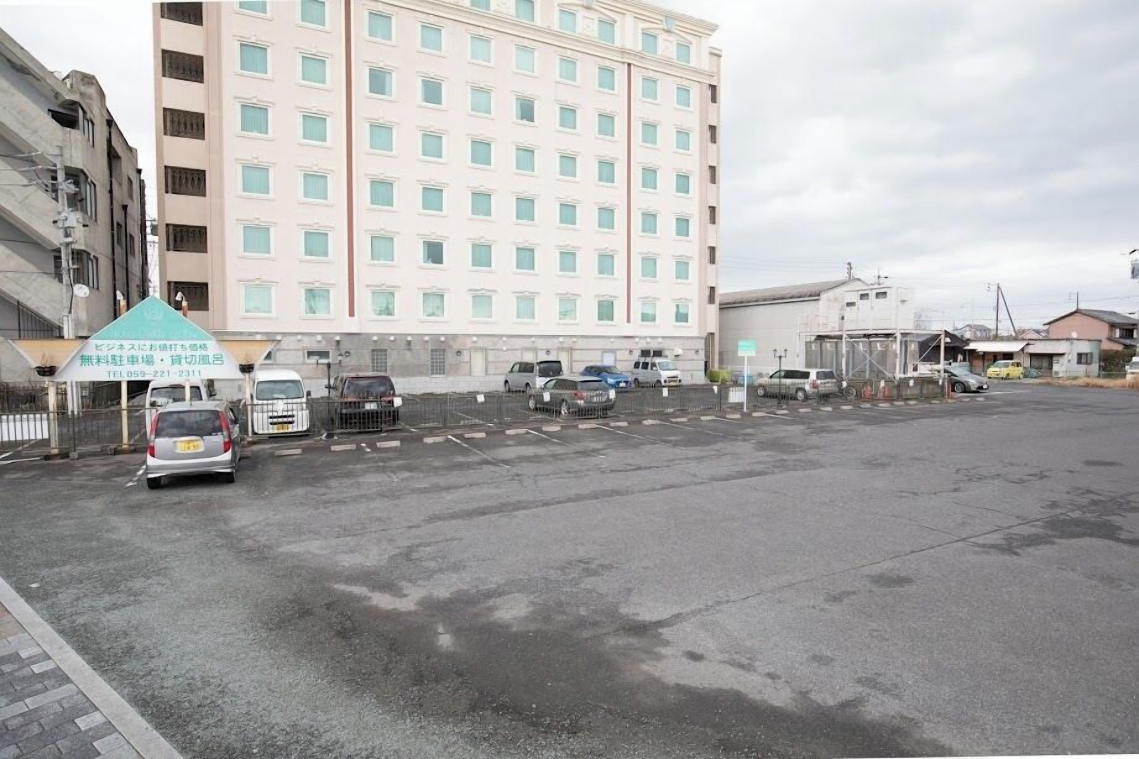 A parking lot with several cars and a building with multiple windows in the background.