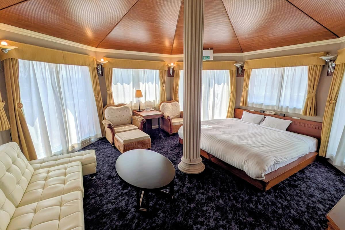 Um quarto com cama, sofá, mesa e cadeira.