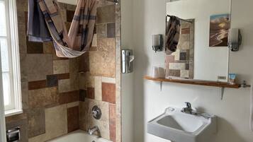 Une salle de bain équipée d’une douche, d’un lavabo, d’un miroir et d’un porte-serviettes.