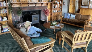 A cozy living room with a fireplace, wooden furniture, and a bookshelf filled with books and decorative items. - Florence Lighthouse Inn (Florence)
