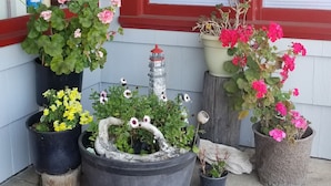 A porch with potted plants and a red mat. - Florence Lighthouse Inn (Florence)