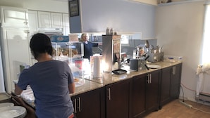 A kitchen with a countertop, cabinets, and a person preparing food. - Florence Lighthouse Inn (Florence)