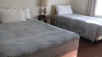 A hotel room with two beds, a nightstand with a lamp, and two framed pictures on the wall.