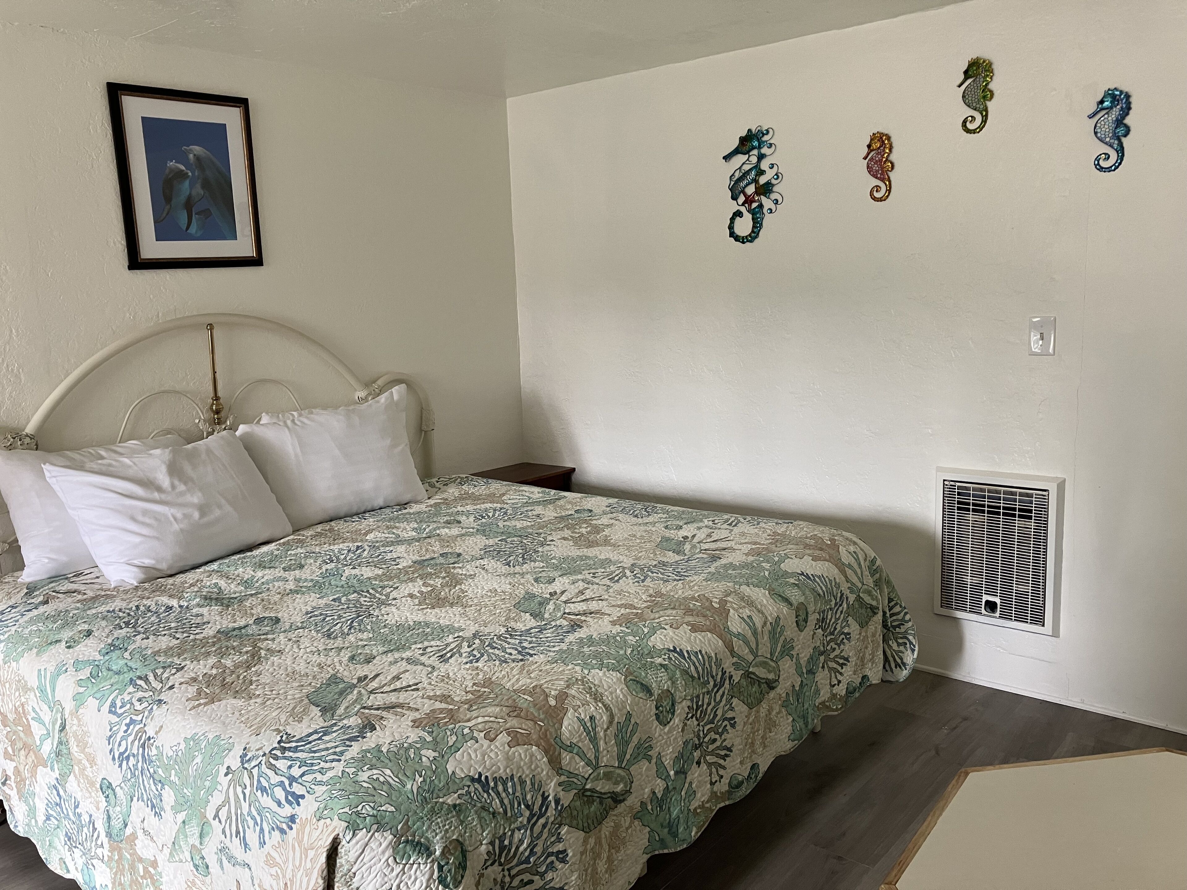 Un dormitorio con una cama, un cuadro en la pared y decoración de caballitos de mar.
