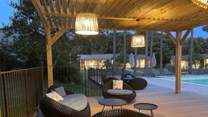 An outdoor deck with wicker furniture, a pool, and a wooden pergola with hanging lights. - Prea Gianca (Bonifacio)