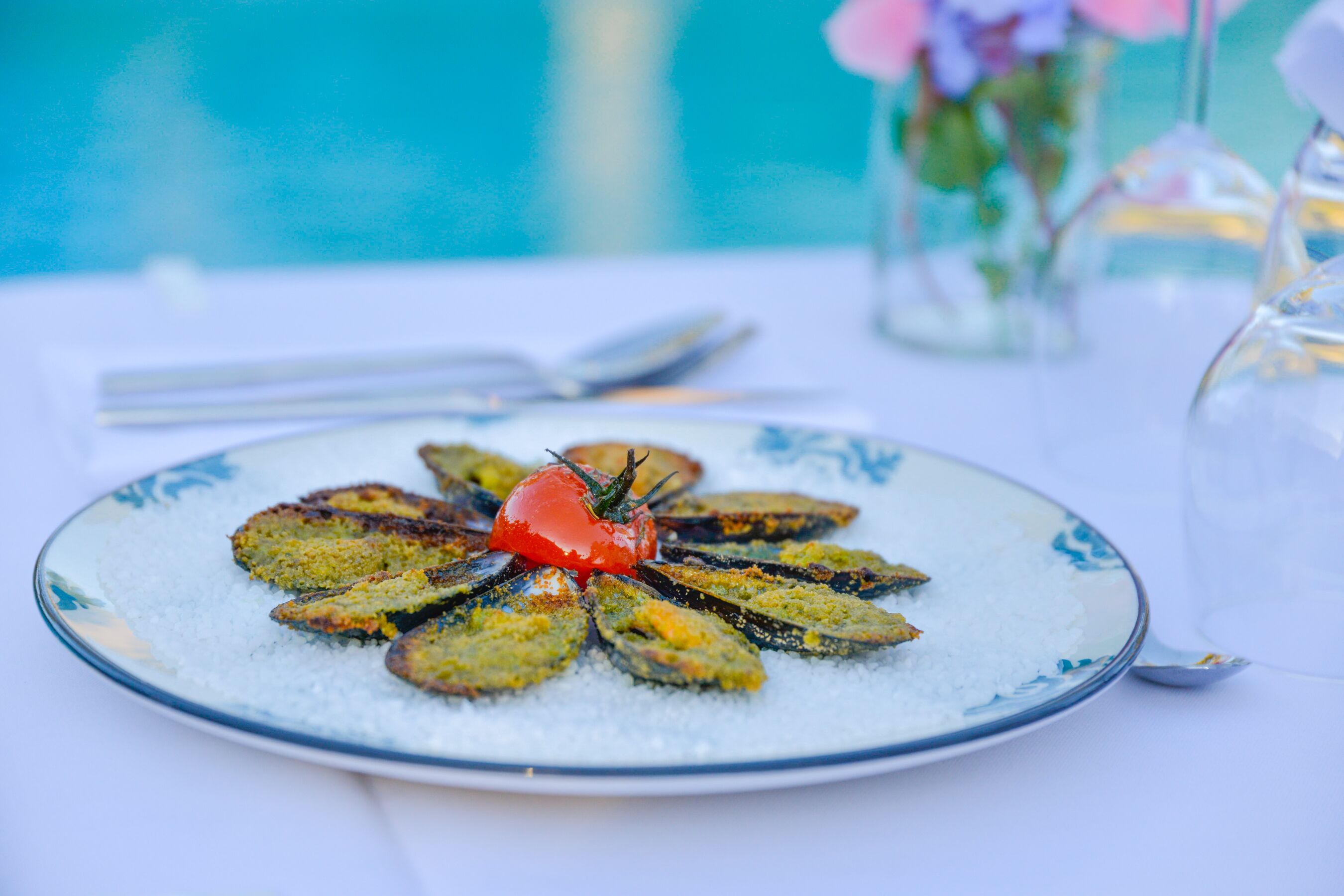 A plate of food with a decorative tomato centerpiece, served on a white table with a blue pattern.