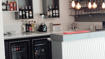 Un área de bar moderna con estantes llenos de botellas de licores, una licuadora y una barra.