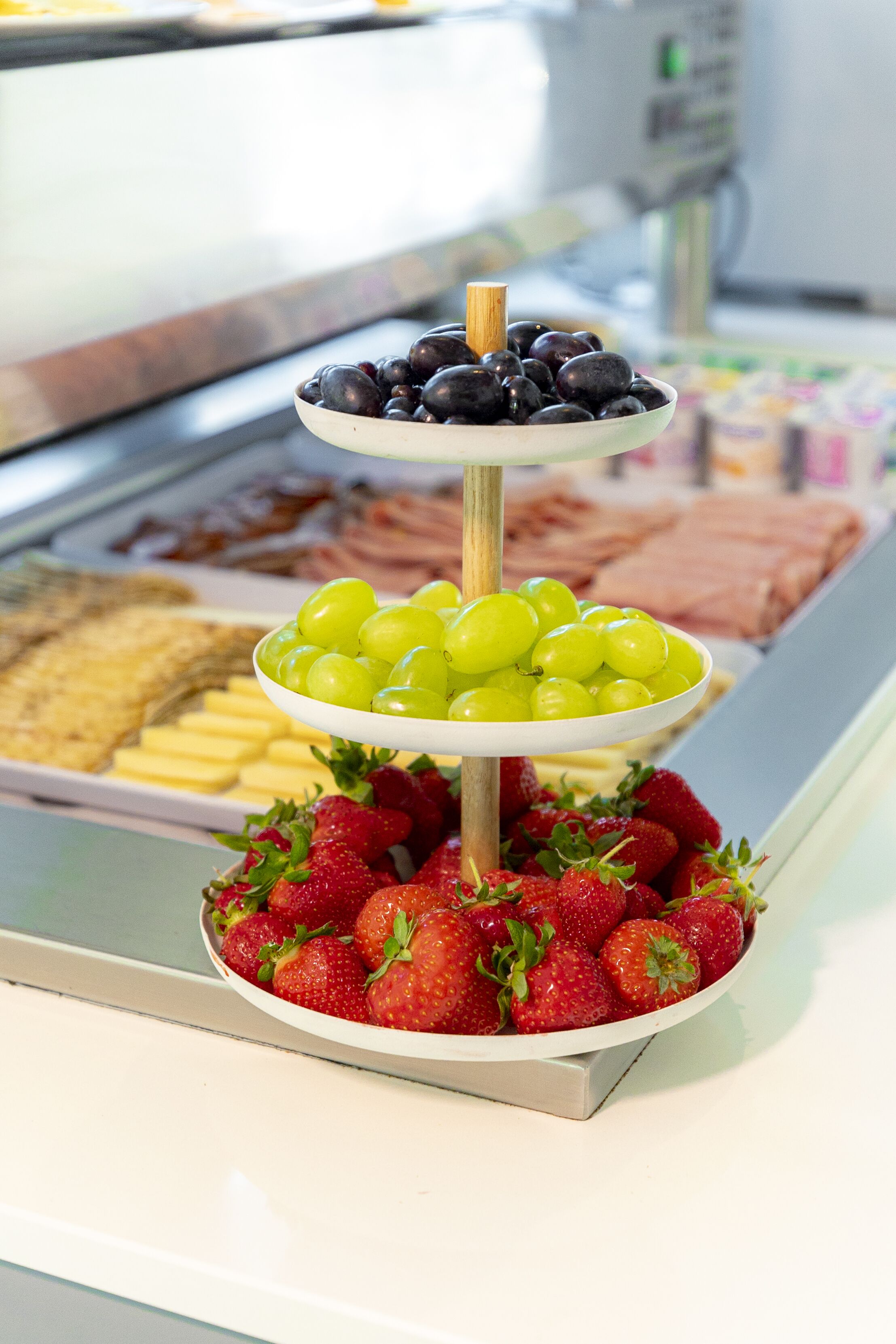 Una exhibición de fruta de tres niveles con uvas, fresas y arándanos.