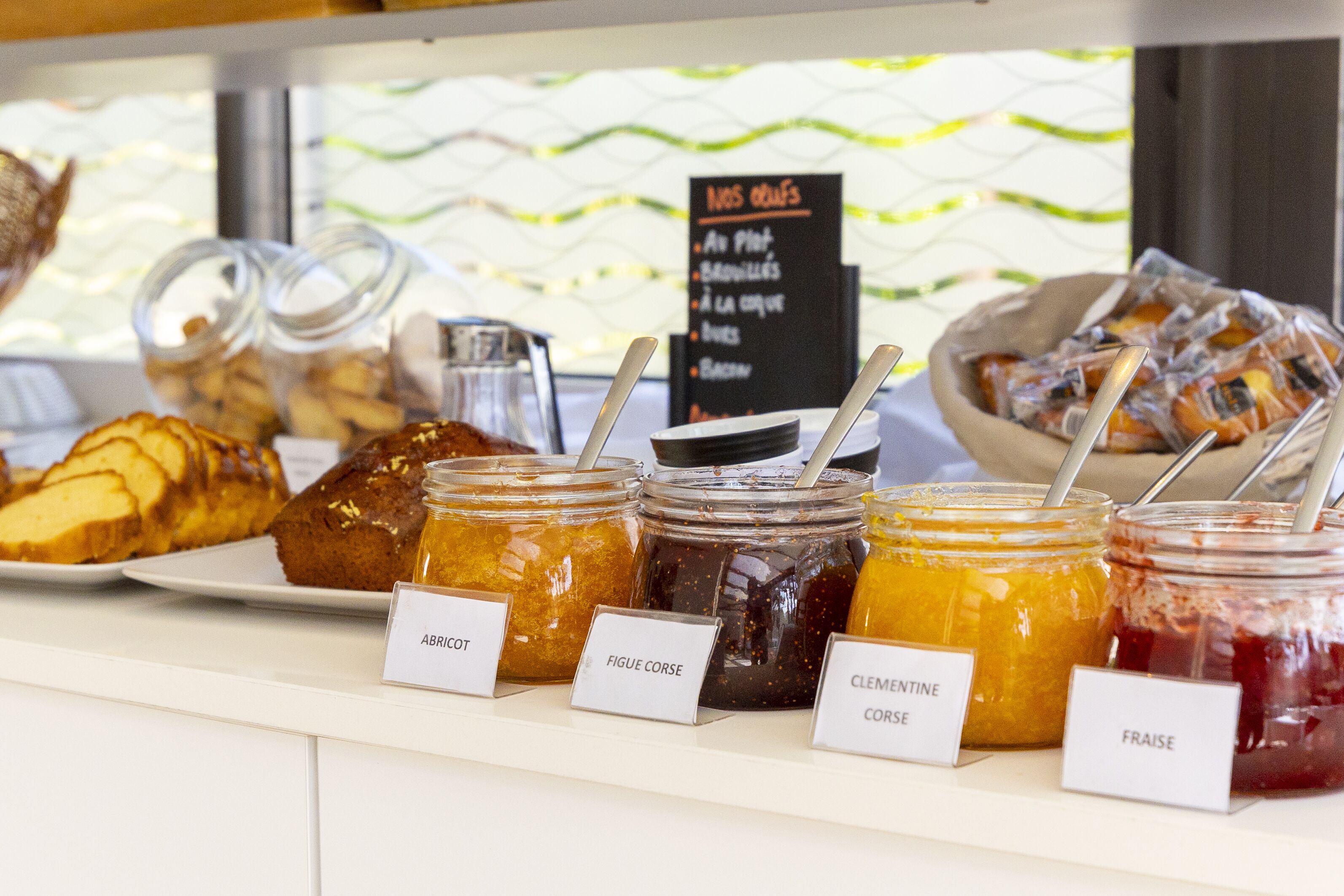 A display of various jams and pastries with labels indicating their names.