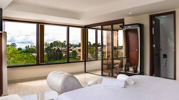 Una habitación de hotel moderna con una cama grande, una zona de estar y un balcón con vistas a la ciudad.