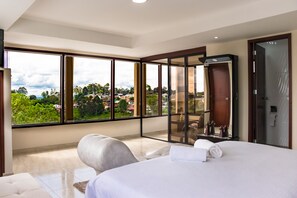 Una habitación de hotel moderna con una cama grande, una zona de estar y un balcón con vistas a la ciudad.