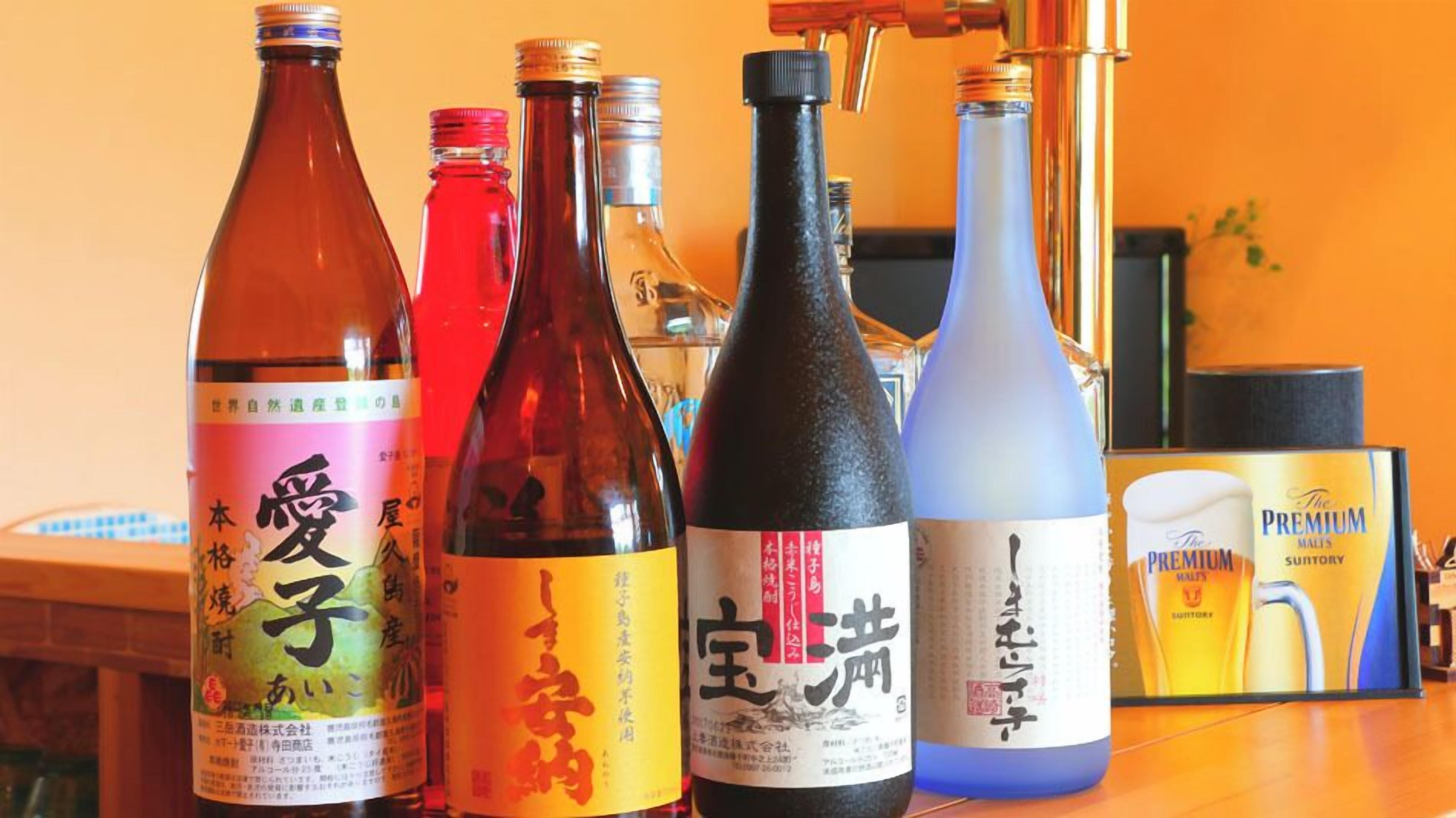 Bottles of Japanese liquor on a table with a laptop and a book in the background.