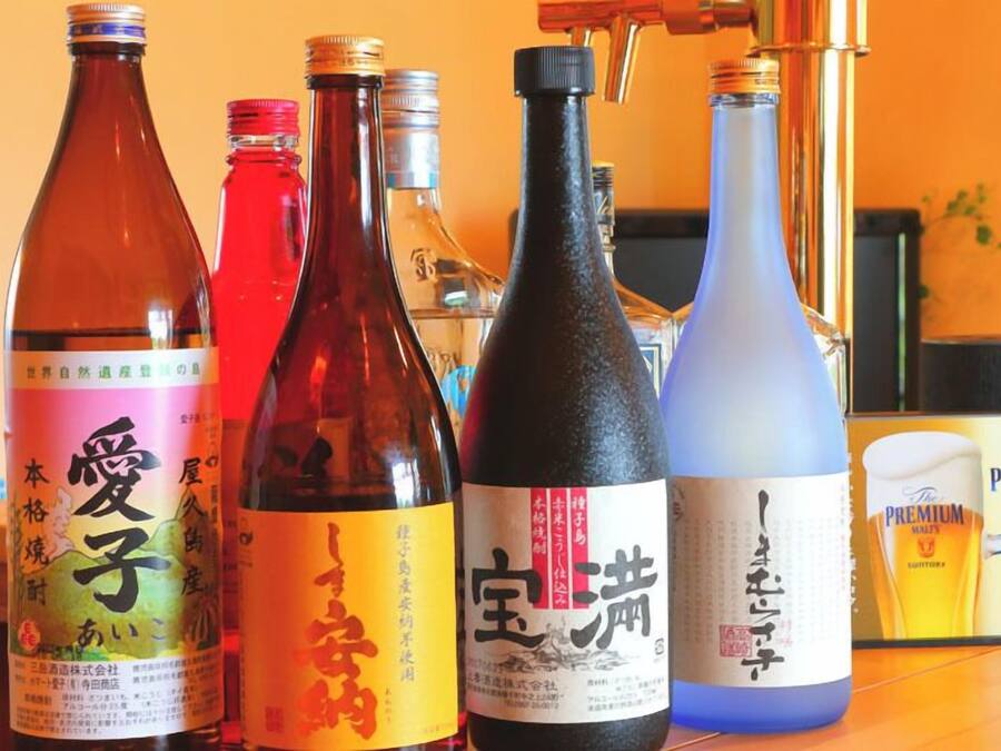 Bottles of Japanese liquor on a table with a laptop and a book in the background.