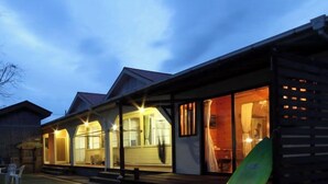 A wooden building with large windows and a visible surfboard. - Tanegashima Minshuku Yu-yu (Minamitane)