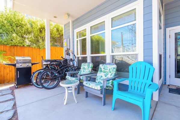 Un patio couvert avec des meubles d’extérieur, un barbecue et des vélos.