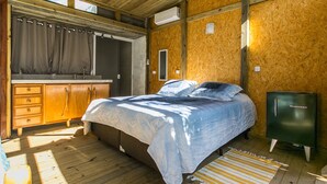 A bedroom with a bed, wooden wardrobe, and a small cabinet. - Guarda Beach House - Hostel (Palhoça)