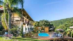 A pool area with a wooden deck, a bicycle, and a bar area. - Guarda Beach House - Hostel (Palhoça)