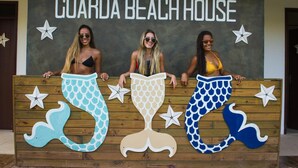 Three mermaid tails in front of a sign that reads "GUARDA BEACH HOUSE". - Guarda Beach House - Hostel (Palhoça)