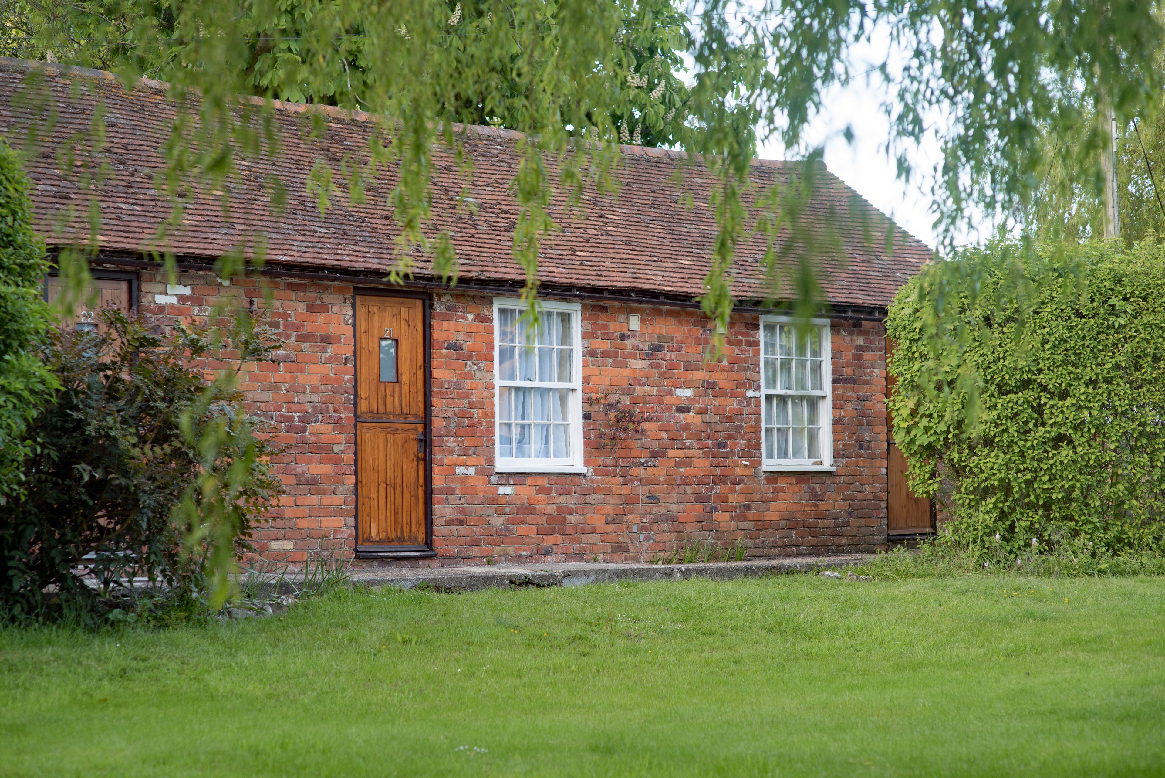 A brick house with a wooden door and two windows.